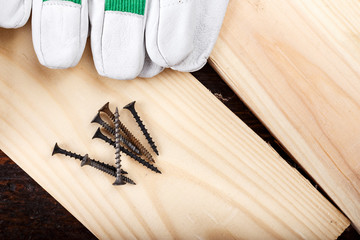 Work gloves and carpenter tools lie on a brown wooden table. view from above. space for text.