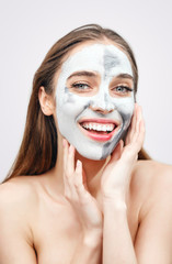 Beautiful cheerful girl with mask for facial skin care