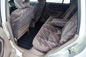 Close-up on rear seats with striped fabric upholstery in the interior of an old Japanese car in gray after dry cleaning