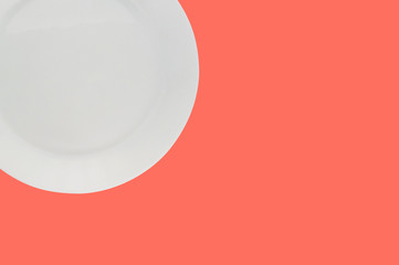 One ceramic circle fragile plate on background of living coral color with copy space for your text....