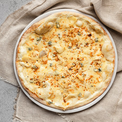 Cheesy pizza decorated with chopped nuts closeup