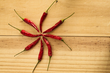 Star of dried red raw hot chili cayenne pepper on a wooden plate. Spicy food. Top view, flat