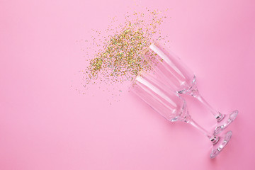 Champagne glasses with golden confetti on pink color paper background minimal style