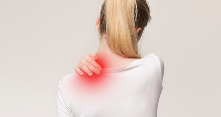 Obraz premium Unhappy woman suffering from pain, massaging neck