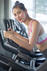 Fototapeta na wymiar asian young fitness woman in sportswear exercising with biking in sport gym club . girl workout on bike machine