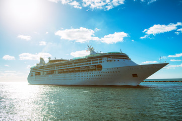 Bright vacation scene of golden sunset shining behind a cruise ship with lens flare against bright...