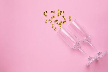 Champagne glasses with golden confetti on pink color paper background minimal style