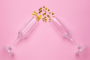 Champagne glasses with golden confetti on pink color paper background minimal style