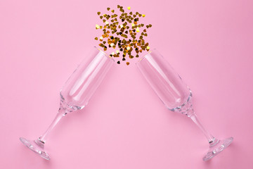 Champagne glasses with golden confetti on pink color paper background minimal style