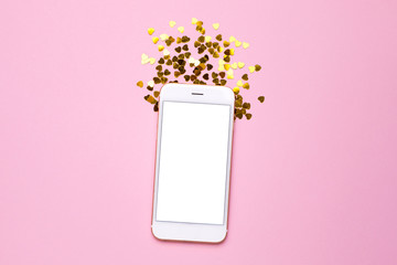 Mobile phone with white empty screen on pink color paper background with golden heart confetti