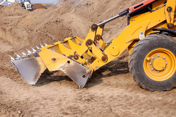 Excavator loader working at ground area, digging process. Yellow bucket. Outdoors, copy space.