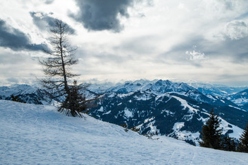 A picture from the sunny day in austrian Alps. The visibility is great, the nature is very nice. The peaks of the mountains are hiding in some clouds. Only few trees on the peaks. 
