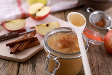 homemade apple jam , apple puree, with cinnamon, fresh apples and a wooden spoon on wooden rustic table