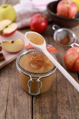 homemade apple jam , apple puree, with cinnamon, fresh apples and a wooden spoon on wooden rustic table