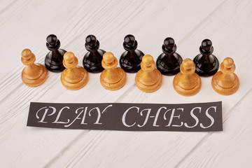 Collection of chess pawns on white background. Set of chess pieces and black paper card with...