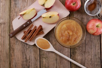 Fototapeta na wymiar homemade apple jam, with fresh apples and spices with wooden spoon on wooden rustic table