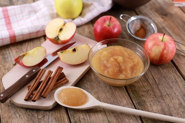 homemade apple jam, with fresh apples and spices with wooden spoon on wooden rustic table