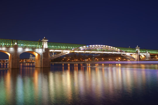 Moskva River in the lights reflections and Andreevsky (Pushkinsky) pedestrian bridge at spring night time. Long exposure image.