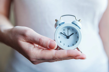 Female woman hands holding ringing twin bell vintage classic alarm clock. Rest hours time of life...