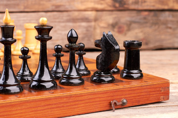 Black chess pieces on chess board. Set of chess figures placed on chess board, cropped image. Game that sharpen your mind.