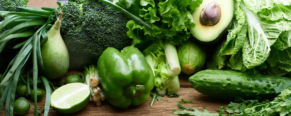 Fresh green vegetables and fruits and greens on a wooden background. Healthy eating concept - obrazy, fototapety, plakaty