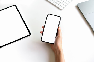 Woman holding Smartphone mockup of blank screen on the table and laptop.
