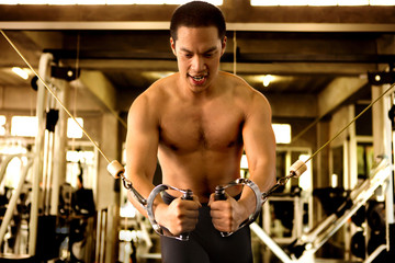 Muscular man pumping up muscles chest with cable crossover at gym in morning light .workout , exercises , bodybuilder training , sport ,