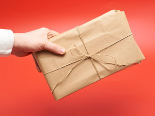 gift wrapped in craft paper in the hands of a man on a red background