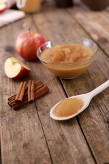 fresh homemade apple jam, apple puree with cinnamon in a bowl with wooden spoon and apples on wooden rustic table