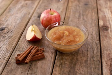 fresh homemade apple jam, apple puree with cinnamon in a bowl and apples on wooden rustic table