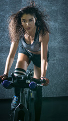 Fototapeta na wymiar Attractive young sportswoman riding stationary bike indoors