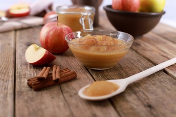homemade apple jam, with fresh apples and spices with wooden spoon on wooden rustic table