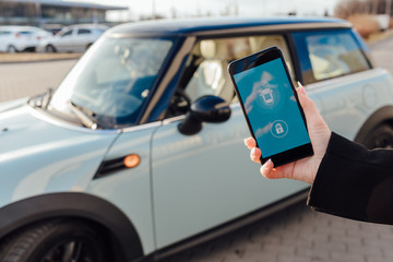 Woman using Smartphone near the car. Mobile phone apps for car owners concept.