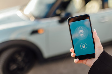 Woman using Smartphone near the car. Mobile phone apps for car owners concept.