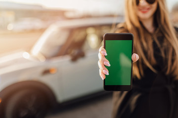 Woman using Smartphone near the car. Mobile phone apps for car owners concept.