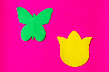 Green butterfly and yellow flower made of soft material on fuchsia background
