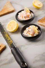 Garnelen Salat mit Lachs Kaviar,  Kräuter, Zitrone, und Vollkorn Toast Brot in schwarzer Schale auf Marmor Hintergrund