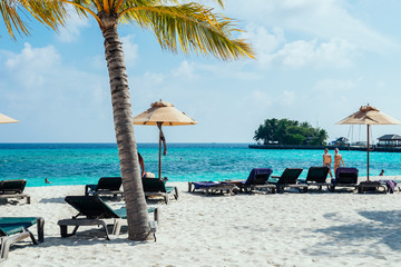 Maldives with turquoise clear water and many palm trees and clouds in the sky