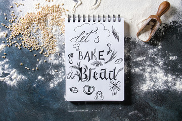 Ingredients for baking bread. Variety of wheat and rye flour, grains, notebook with handwritten lettering over dark blue texture background. Flat lay, space