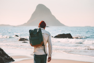 Man with backpack walking on empty beach traveling lifestyle vacations in Norway outdoor solitude emotions