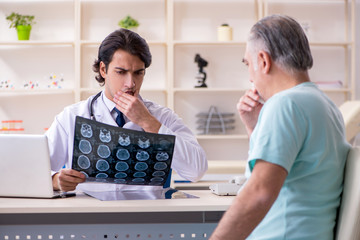 Fototapeta premium Old man visiting young male doctor 