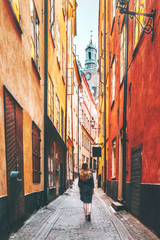 Woman tourist walking alone in Stockholm narrow street traveling lifestyle summer vacations in Sweden - obrazy, fototapety, plakaty