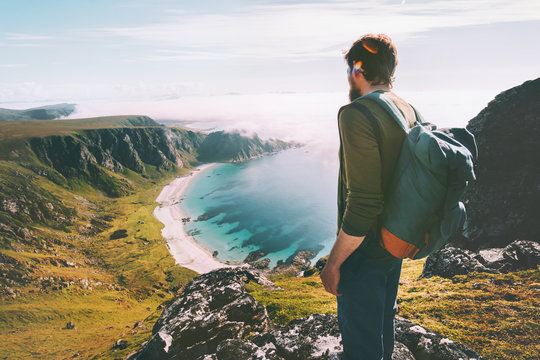 Man admires ocean beach aerial view solo traveling active lifestyle hiking adventure summer vacations in Norway outdoor