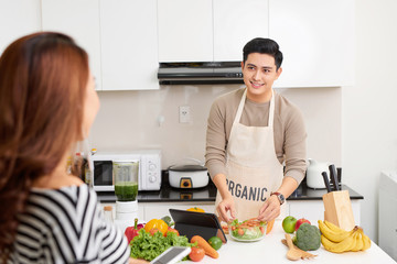 young happy couple cooking together in the kitchen at home.