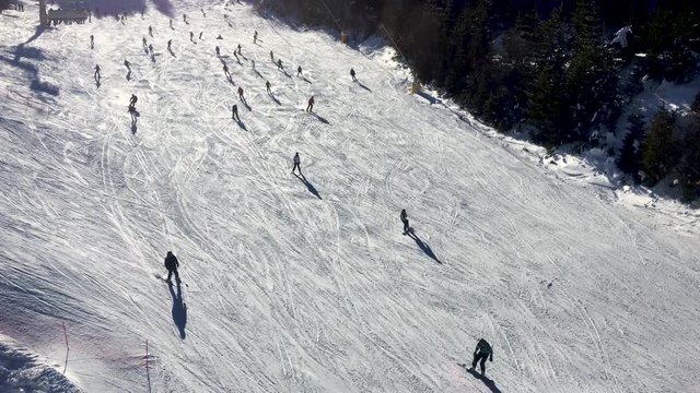 4K aerial video clip of people skiing on a sunny winter mountain