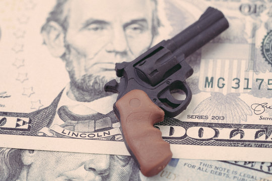Big money in gun industry, gun control policy in united state of america concept, mass shooting protection, miniature toy guns on US dallar bill