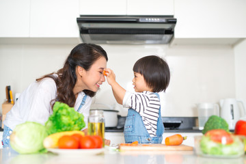 Happy family in the kitchen. Mother and child daughter are preparing the vegetables and fruit.