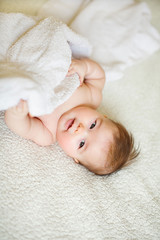 Portrait of cute baby girl lying down on a bed.