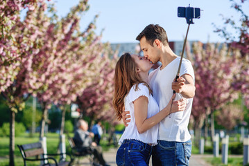 Obraz premium Passion and love concept. Man and woman kissing in blooming garden on spring day. Couple hugs near sakura trees. Couple in love spend time in spring garden.