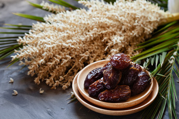 Bowl of raw organic medjool dates with leaves and flowers of date palm
